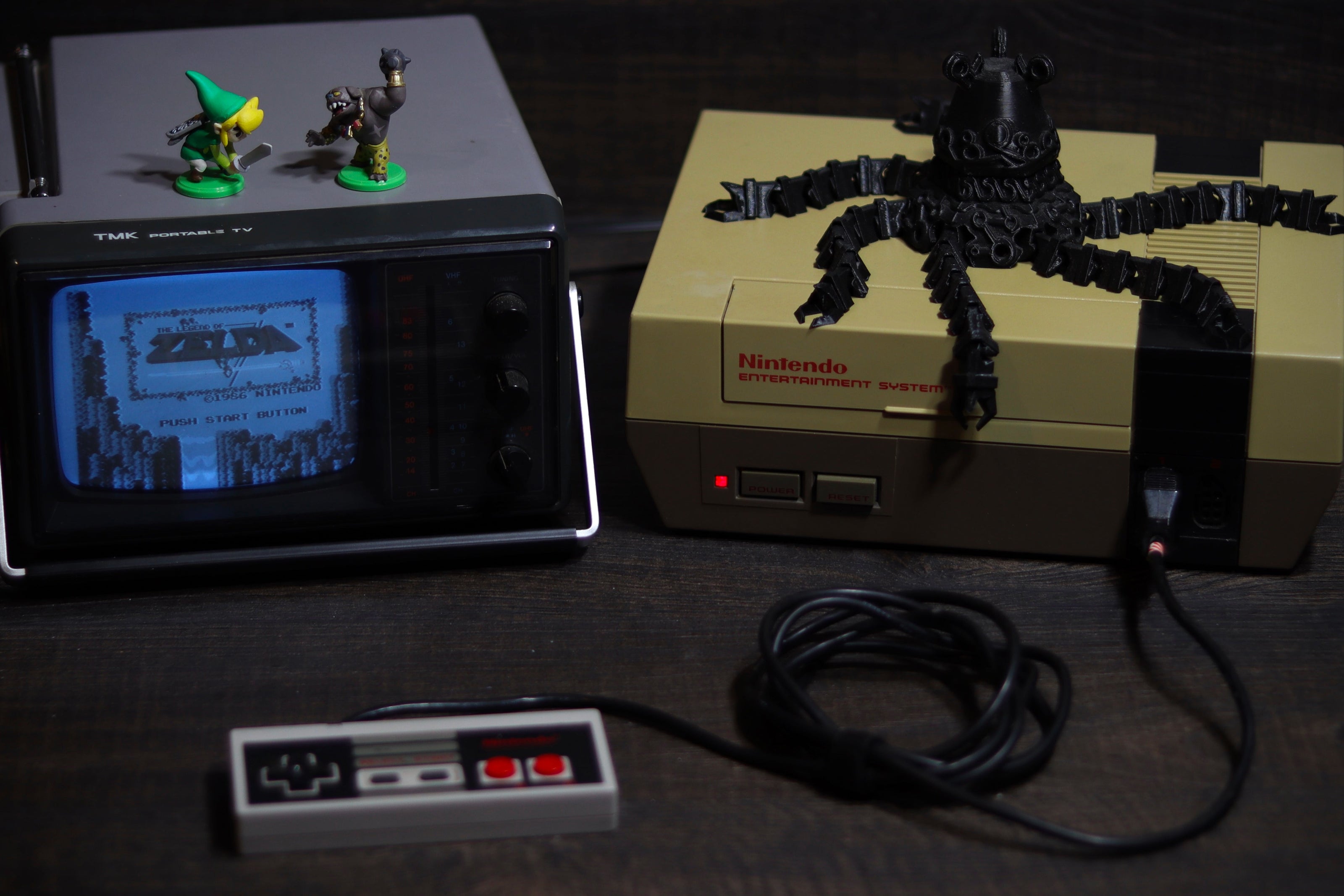 Miniature Nintendo Entertainment System with classic games on screen, surrounded by gaming accessories.